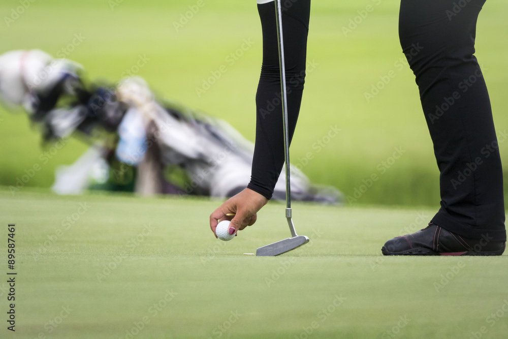 Obraz premium Female golfer marks her ball position on a green