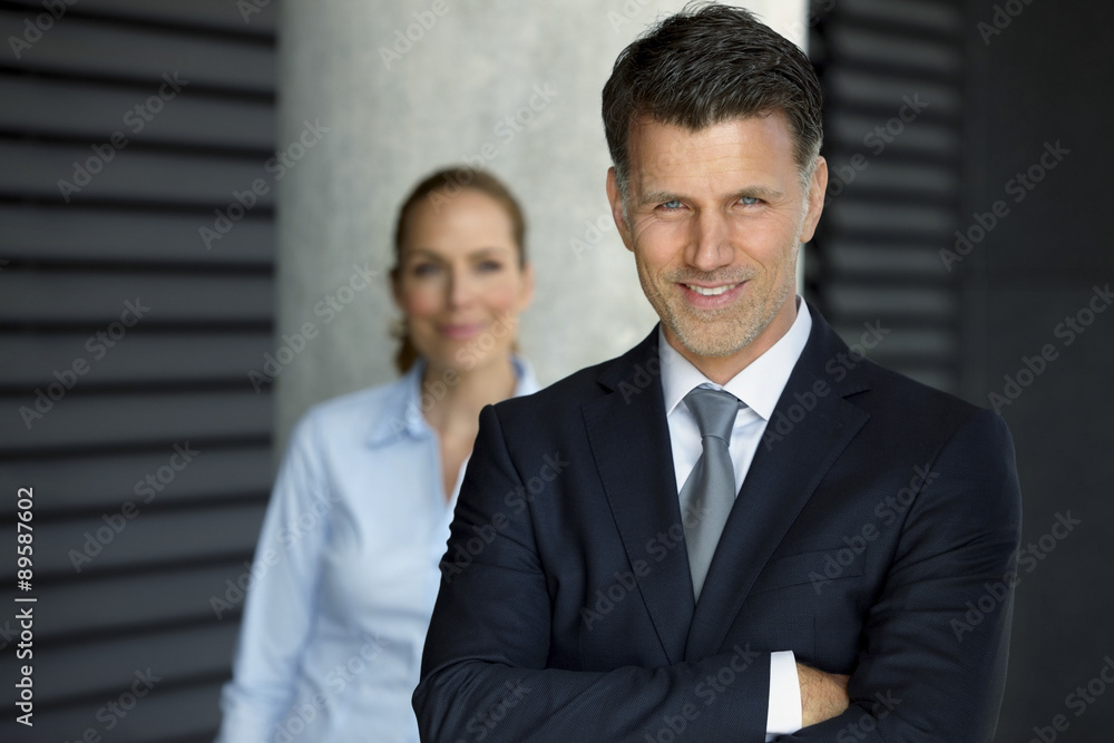 Portrait of successful businessman with colleague in the background Portrait of successful businessman with colleague in the background