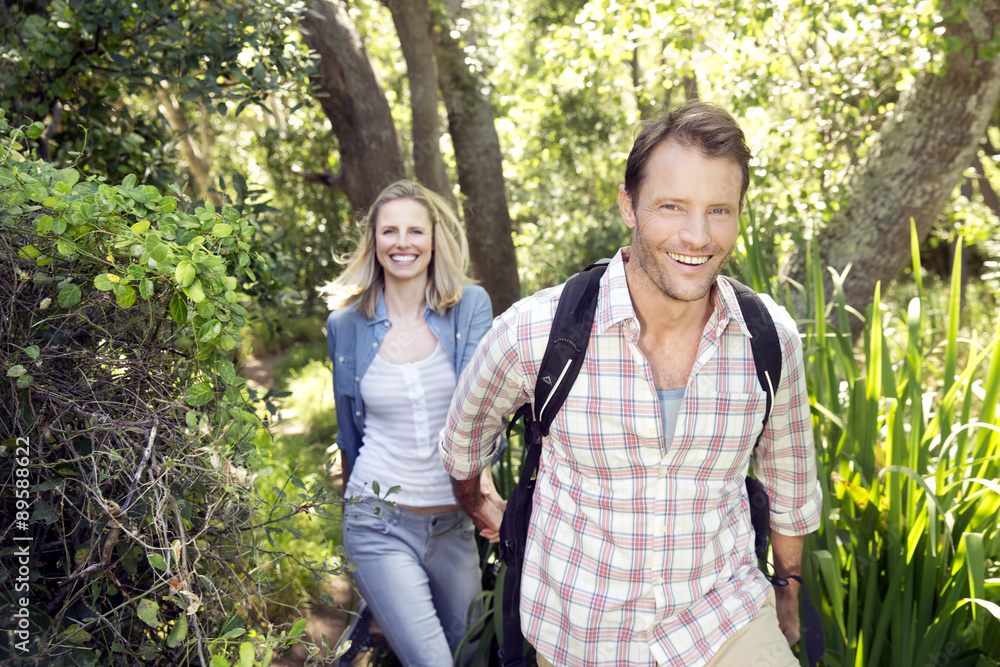 Smiling couple hiking hand in hand in forest Smiling couple hiking hand in hand in forest