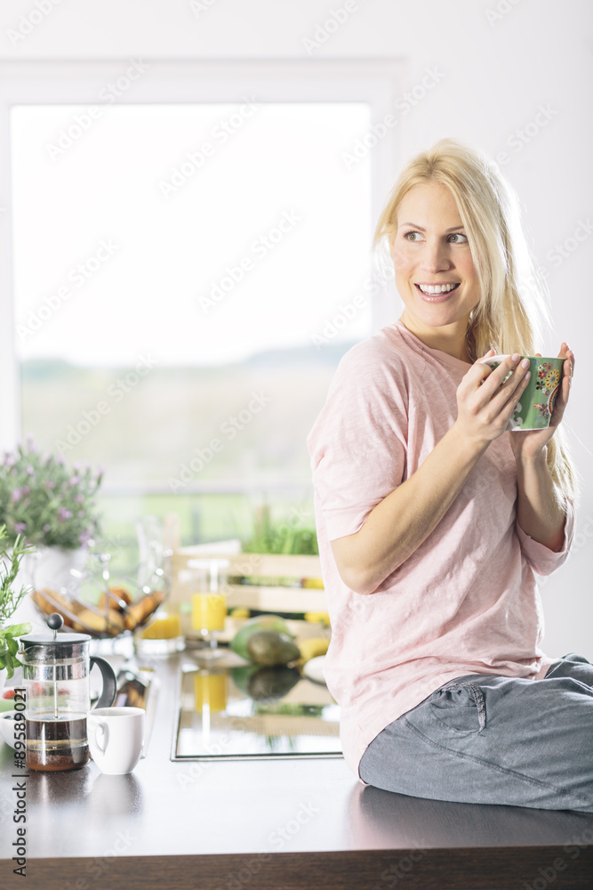 Portrait of smiling young woman with cup of coffee in the kitchen Portrait of smiling young woman with cup of coffee in the kitchen