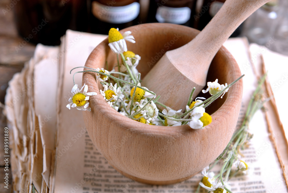 Old book with dry flowers in mortar and bottles on table close up Old book with dry flowers in mortar and bottles on table close up