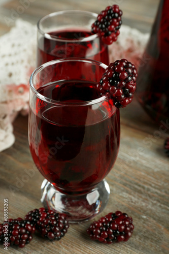 Glasses of blackberry juice on wooden table, closeup