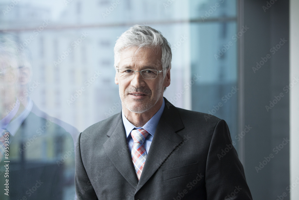 Businessman standing at window, portrait Businessman standing at window, portrait