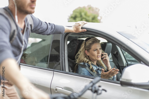 Man on bicycle and woman in car in traffic jam photo