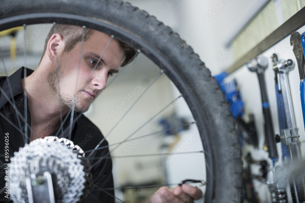 Young man working in bicycle shop Young man working in bicycle shop