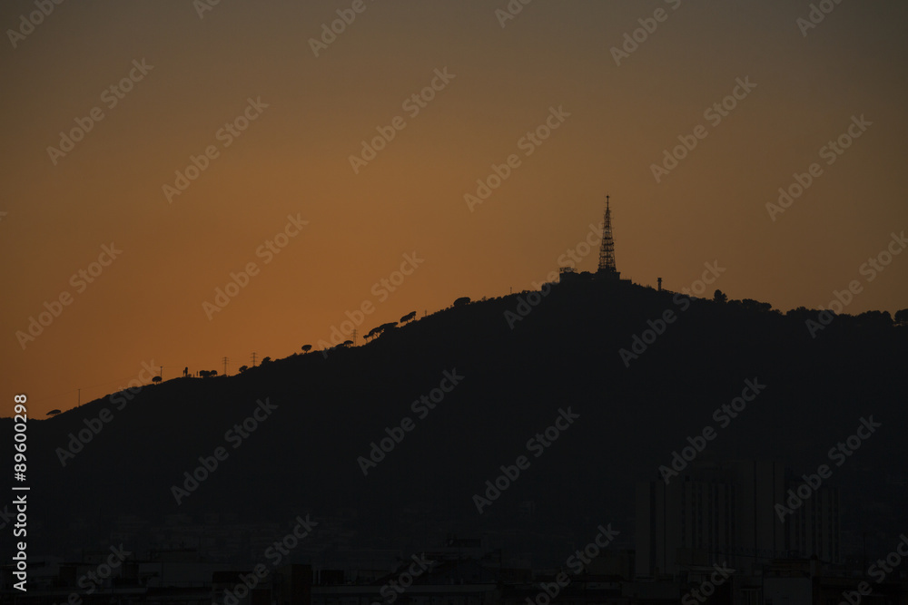 Warm glow of sunset creating a silhouette on a hilltop in the distance