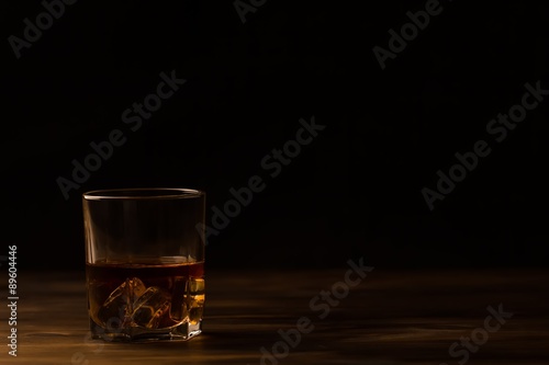 glass of whiskey with ice on a wooden table. Cognac, brandy.