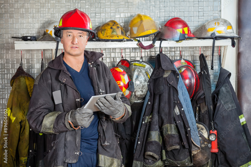 Obraz premium Fireman Holding Digital Tablet At Fire Station