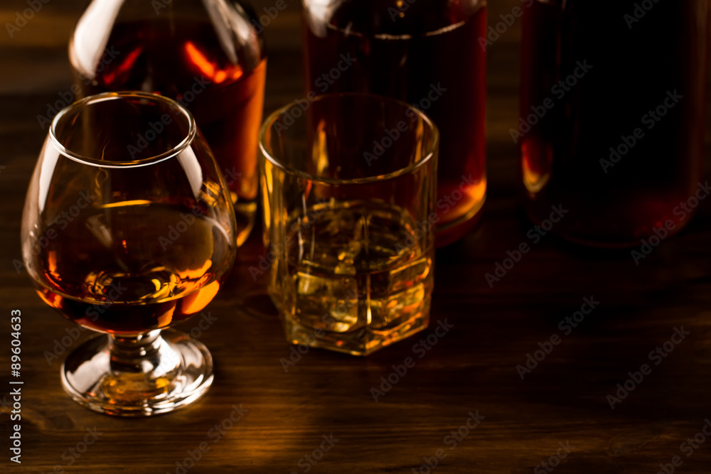 glass of whiskey with ice and a bottle on a wooden table. Cognac, brandy. glass of whiskey with ice and a bottle on a wooden table. Cognac, brandy.