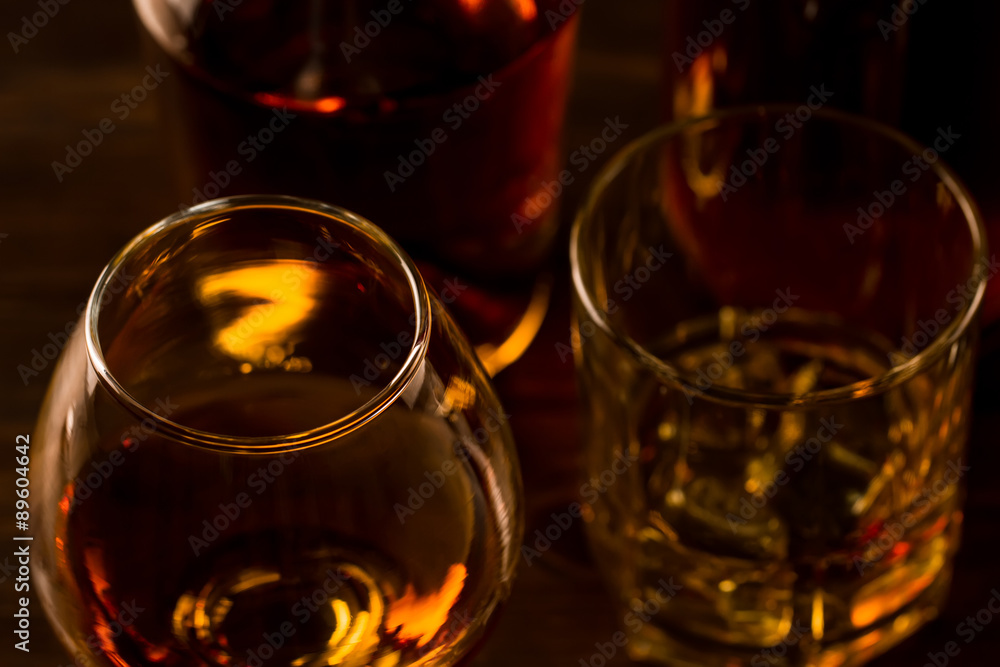 glass of whiskey with ice and a bottle on a wooden table. Cognac, brandy. glass of whiskey with ice and a bottle on a wooden table. Cognac, brandy.