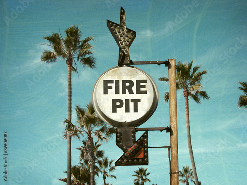 aged and worn vintage photo of fire pit sign with palm trees