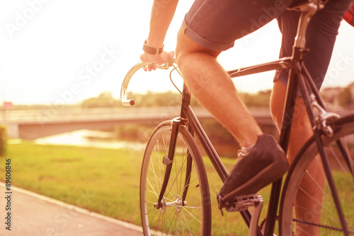 Hipster on bike in the city at sunset