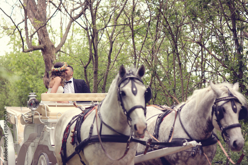 Canvas Print Bride and groom sitting in a white carriage