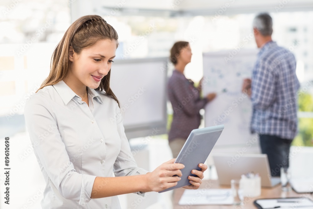 Smiling businesswoman using tablet in a meeting Smiling businesswoman using tablet in a meeting