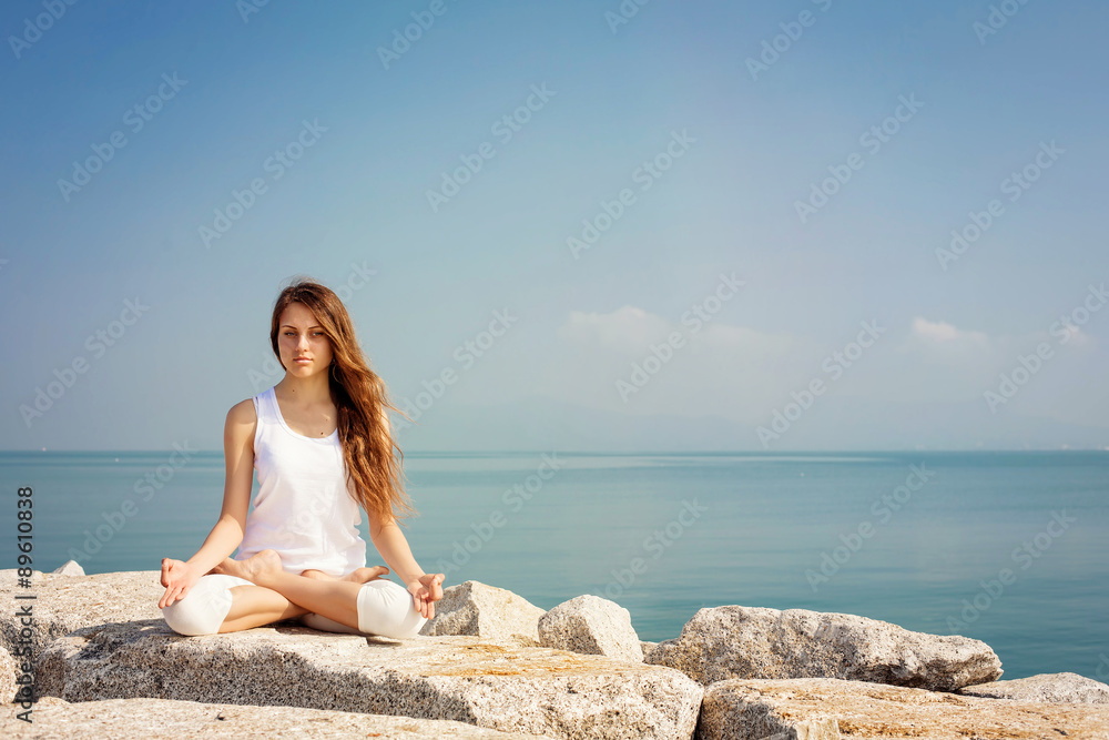 Beautiful young woman practicing yoga and relax in lotus pose at seashore