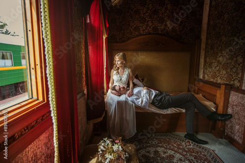 Just Married Bride and Groom Sitting in Luxury Train. Wedding and Honeymoon Travel © Annatamila