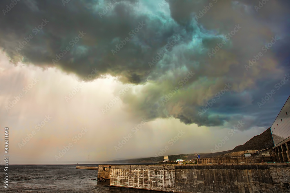 Dark storm clouds and rain over the river and dam