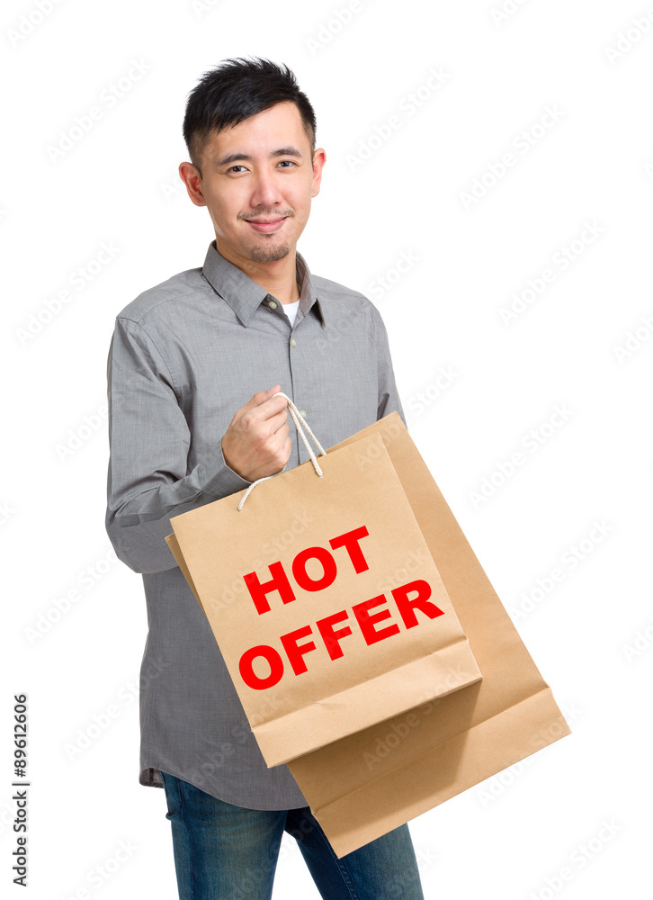 Asian man hold with shopping bag and showing hot offer Asian man hold with shopping bag and showing hot offer