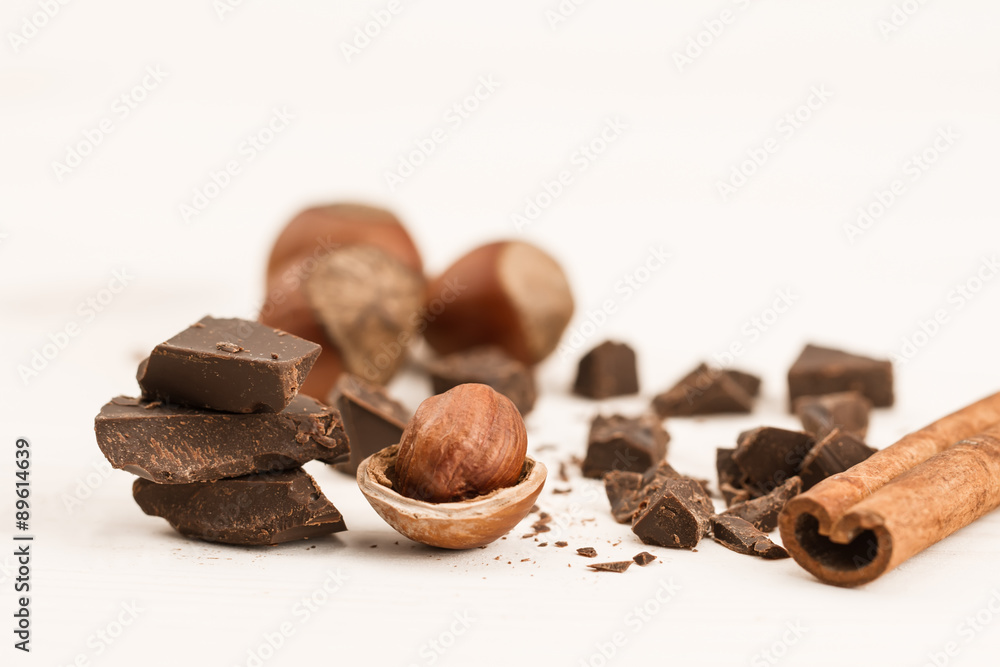Broken chocolate bar, hazelnut and cinnamon on wooden background, close-up Broken chocolate bar, hazelnut and cinnamon on wooden background, close-up