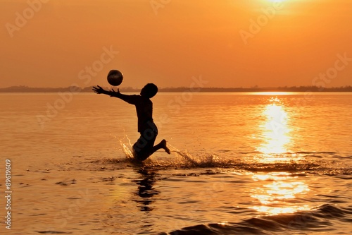 Children playing ball on the beach at sunset