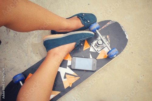 Selfie of young girl with smart phone on skateboard
