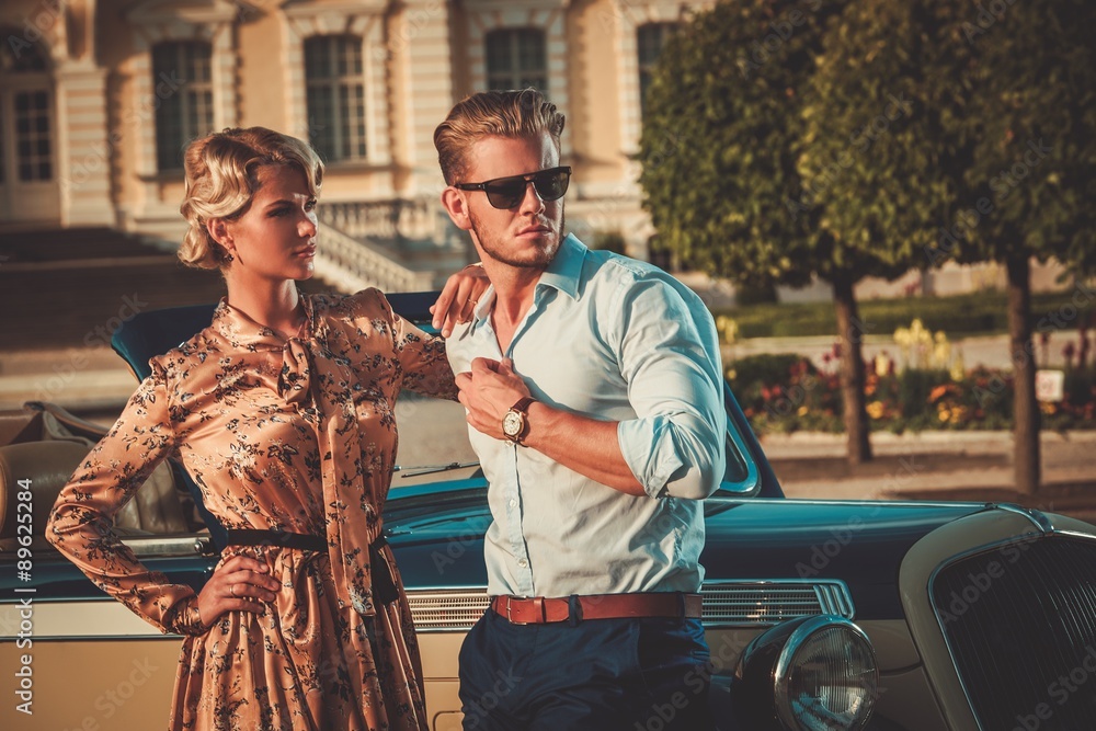 Wealthy couple near classic convertible against royal palace Wealthy couple near classic convertible against royal palace