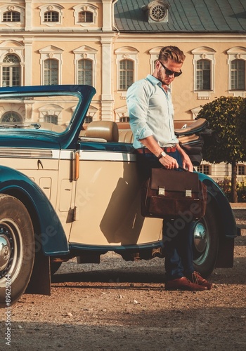 Confident wealthy young man with briefcase near classic convertible © Nejron Photo