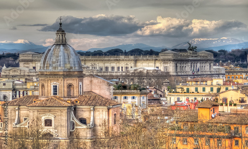 Panoramic view of Rome on the background of clouds and mountains. In the foreground the church Santa Maria in Campitelli. In the distance we see the Altar of the Fatherland. HDR