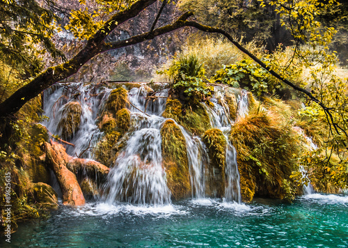 The waterfall flows into the lake in the autumn forest