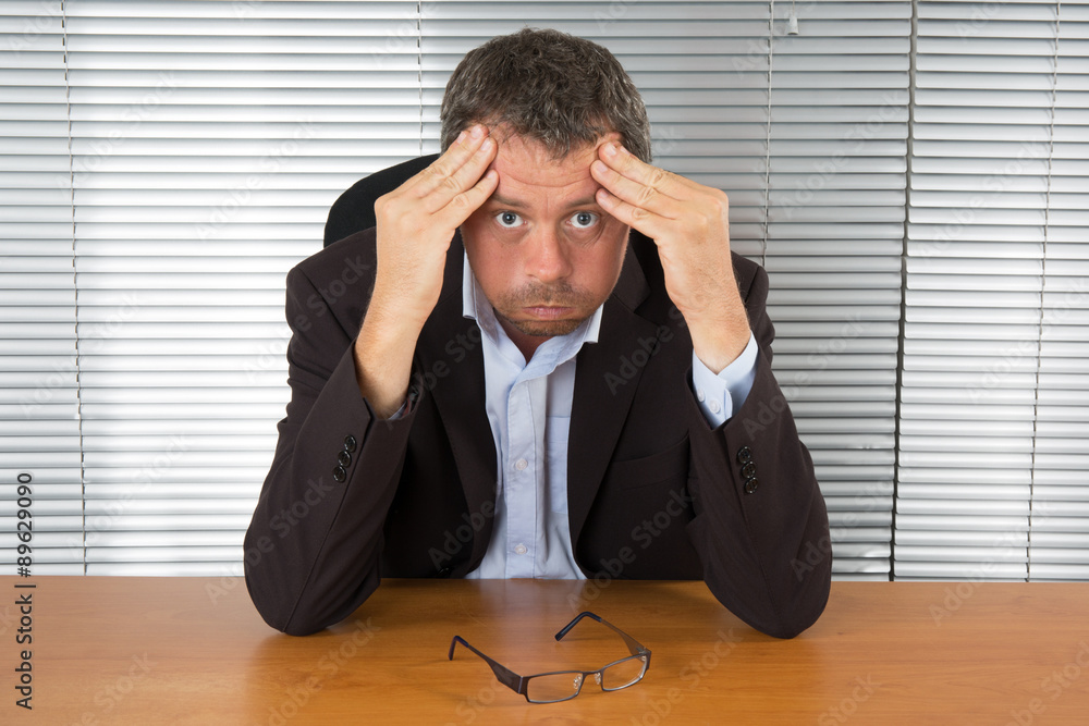 Desperate businessman leaning on both hands behind his laptop Desperate businessman leaning on both hands behind his laptop