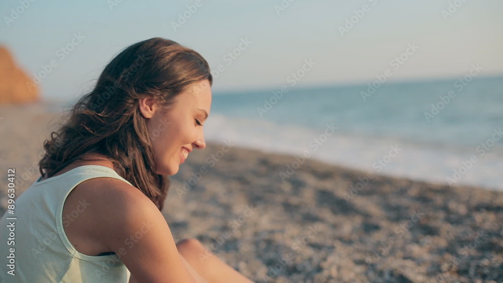 Seductive girl sitting on the beach near the sea touching and Seductive girl sitting on the beach near the sea touching and