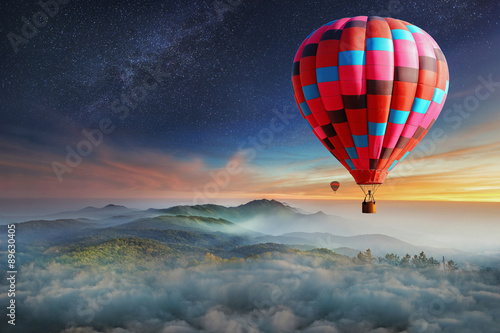 Colorful hot-air balloons flying over the mountain with with stars. Beautiful mountains landscape with clouds at sunset