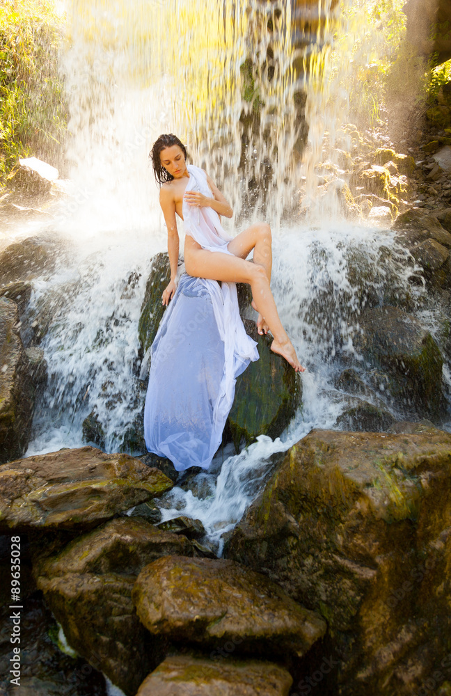 Naked girl sitting on a rock by a waterfall. Naked girl sitting on a rock by a waterfall.