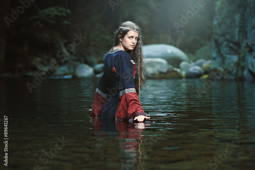 Medieval woman in the middle of a dark stream