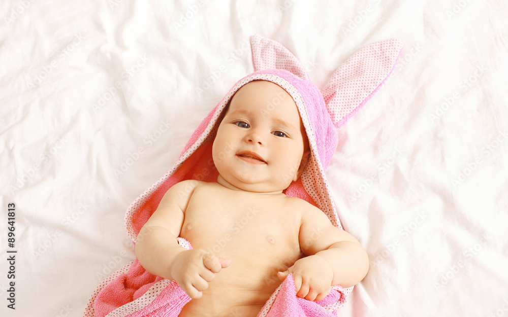 Portrait of cute baby in towel lying on the bed at home, top vie Portrait of cute baby in towel lying on the bed at home, top vie