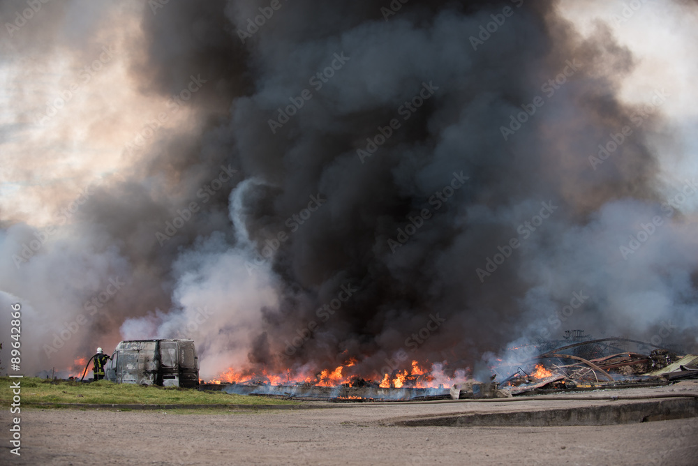 Obraz premium Huge fire of buildings and cars. Firefighters at work.