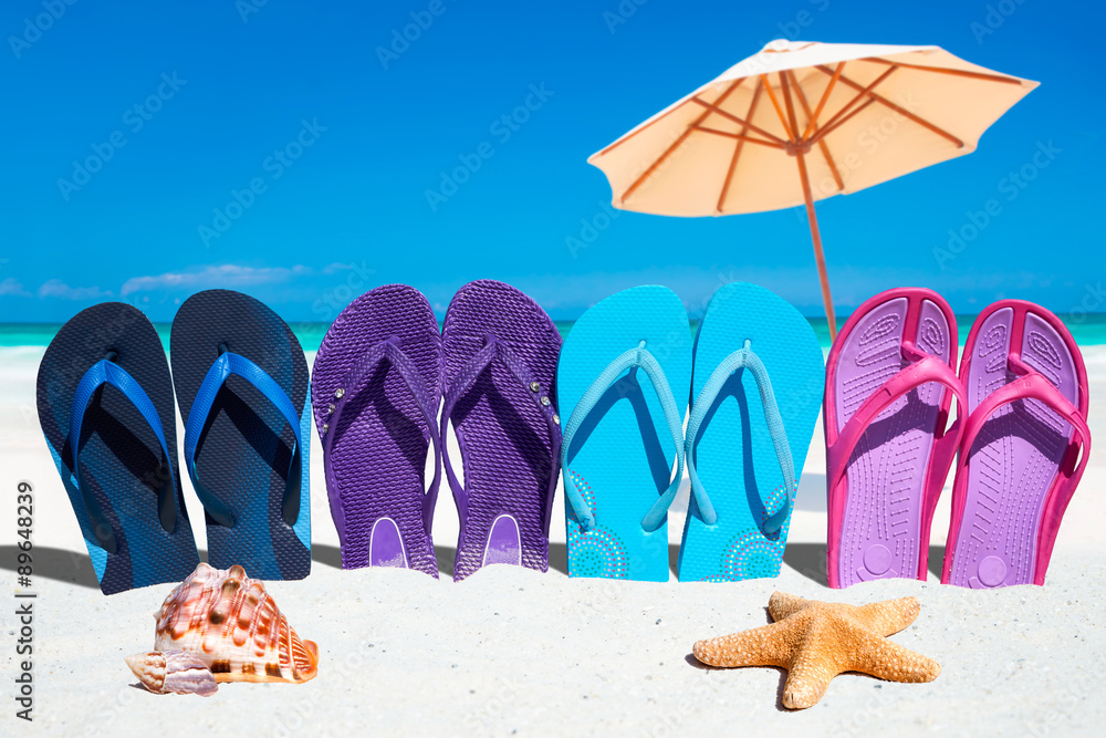 Bunte Flip Flops in einer Reihe mit Muscheln und Sonnenschirm Stock Photo |  Adobe Stock