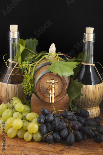 In oak casks with vines and grapes white and black photo