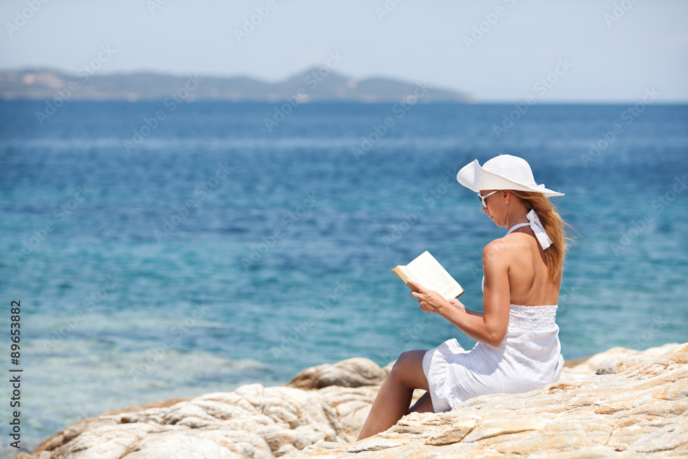 Young Woman Reading Book On The Beach