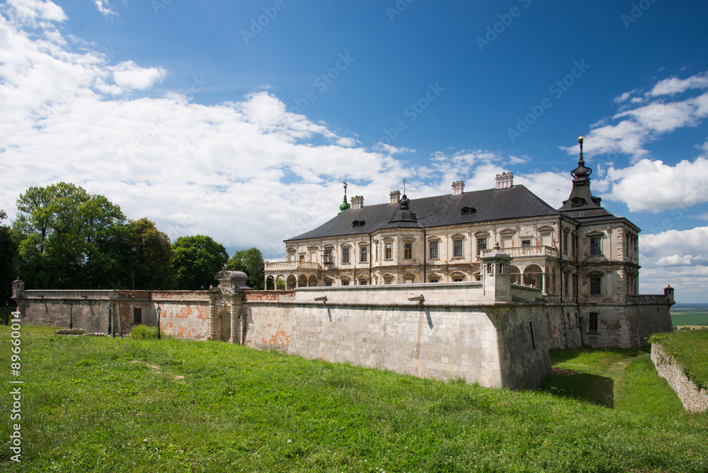 Podgoretsky castle with garden and blue cloudy sky background