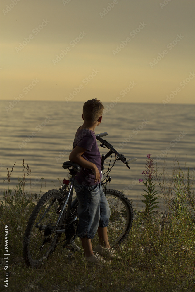 Fototapeta premium boy on a bicycle near the sea in the evening at sunset.