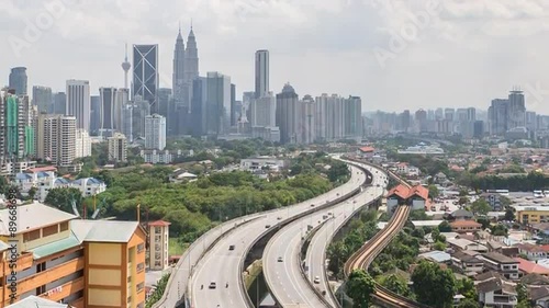 Time lapse HD footage of road lead to Kuala Lumpur city center. Showing moving cars and moving clouds during daylight. Tilt up.