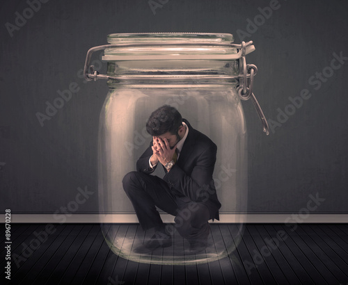 Businessman trapped into a glass jar concept photo