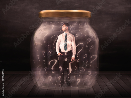 Businessman locked into a jar with question marks concept photo