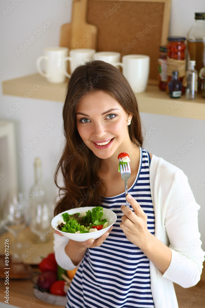 Young woman eating salad and holding a mixed salad Young woman eating salad and holding a mixed salad