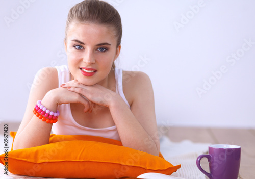 Smiling young woman lying on a white floor with pillow