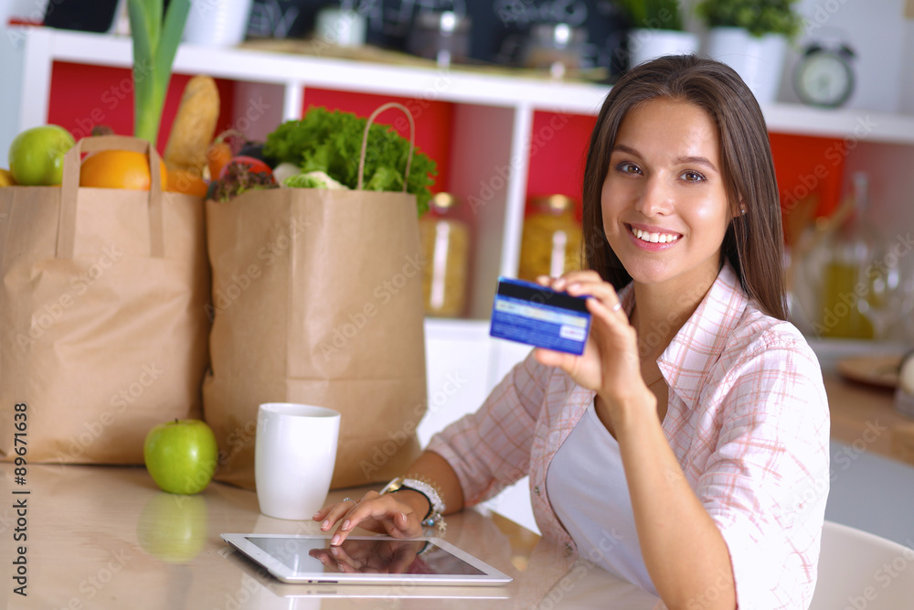Smiling woman online shopping using tablet and credit card in