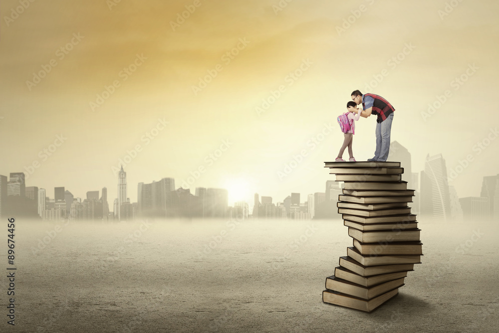 Father kiss his kid above a pile of books Father kiss his kid above a pile of books