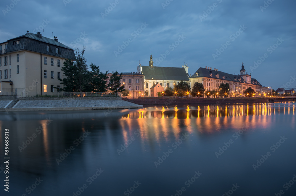 Fototapeta premium Odra river waterfront in Wroclaw, Poland, with university church and main university building, in early morning, seen from Malt Island (Wyspa Slodowa)