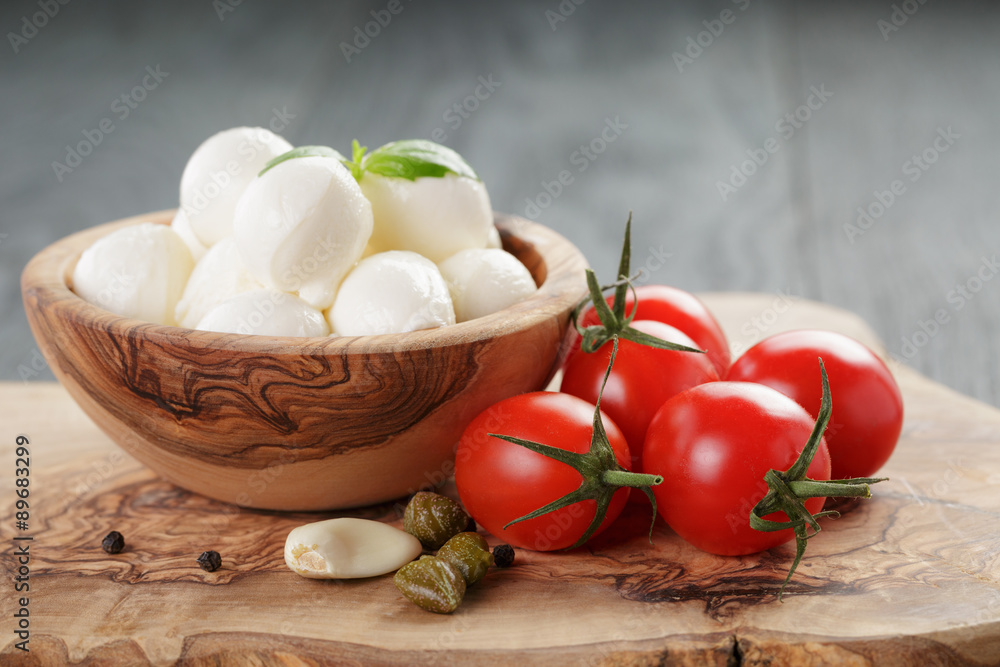 small balls of mozzarella with basil leaves ant tomato